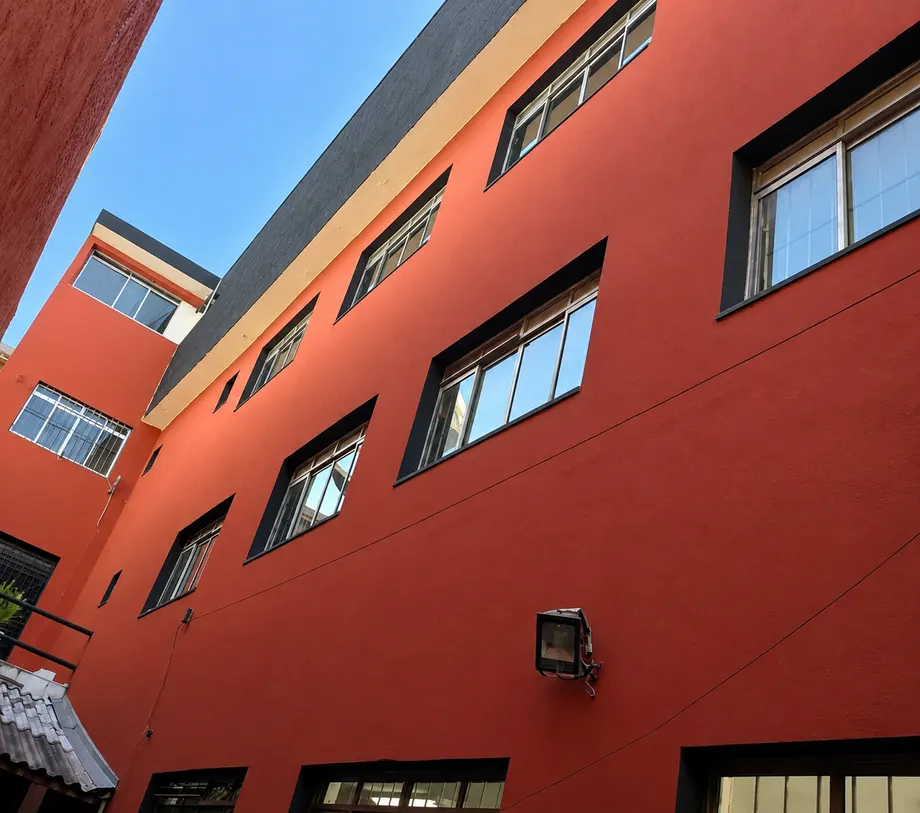 Vista da lateral do prédio vermelho com diversas janelas