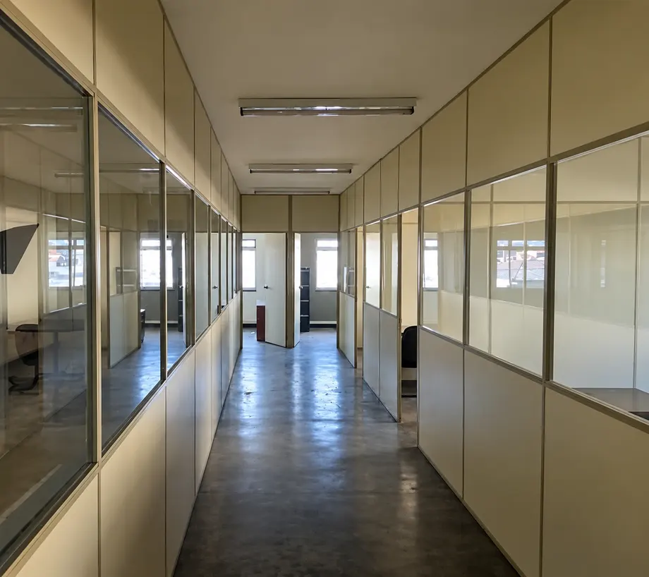 Corredor com divisórias de vidro e acesso a salas