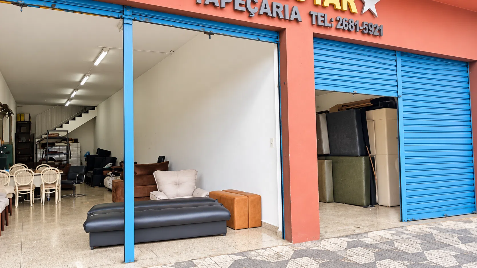 Loja térrea com portas de aço azuis, ampla abertura e área de exposição